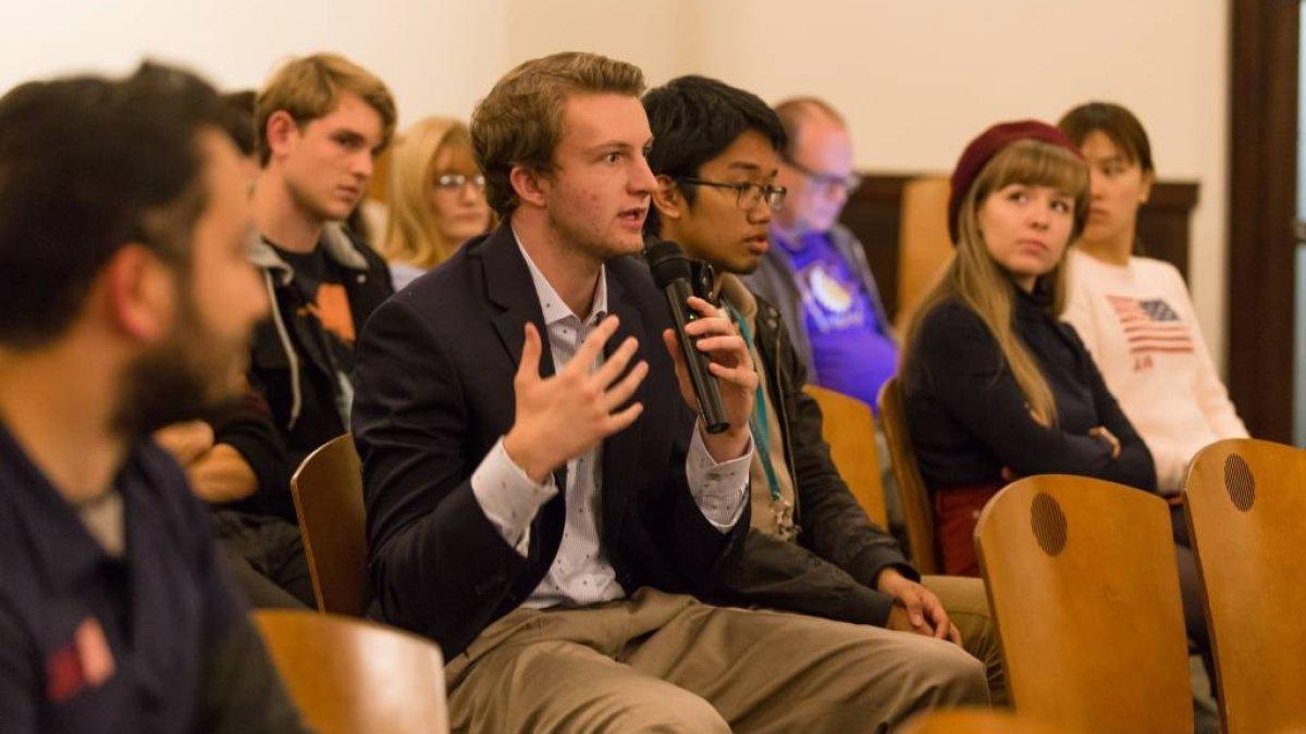 student sitting in a suit with microphone